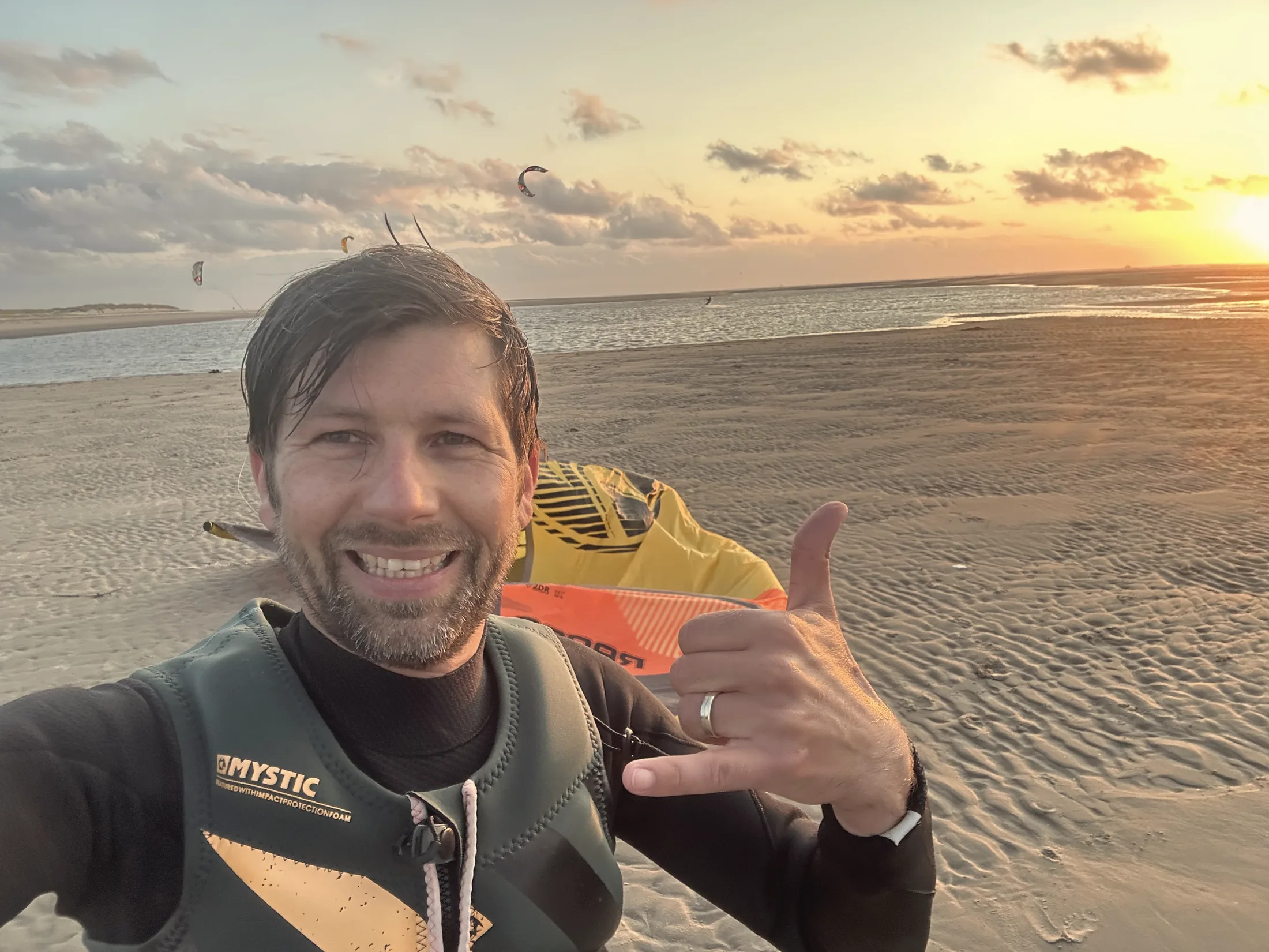 Till am Strand bei Sonnenuntergang, lachend, im Kite-Neoprenanzug
