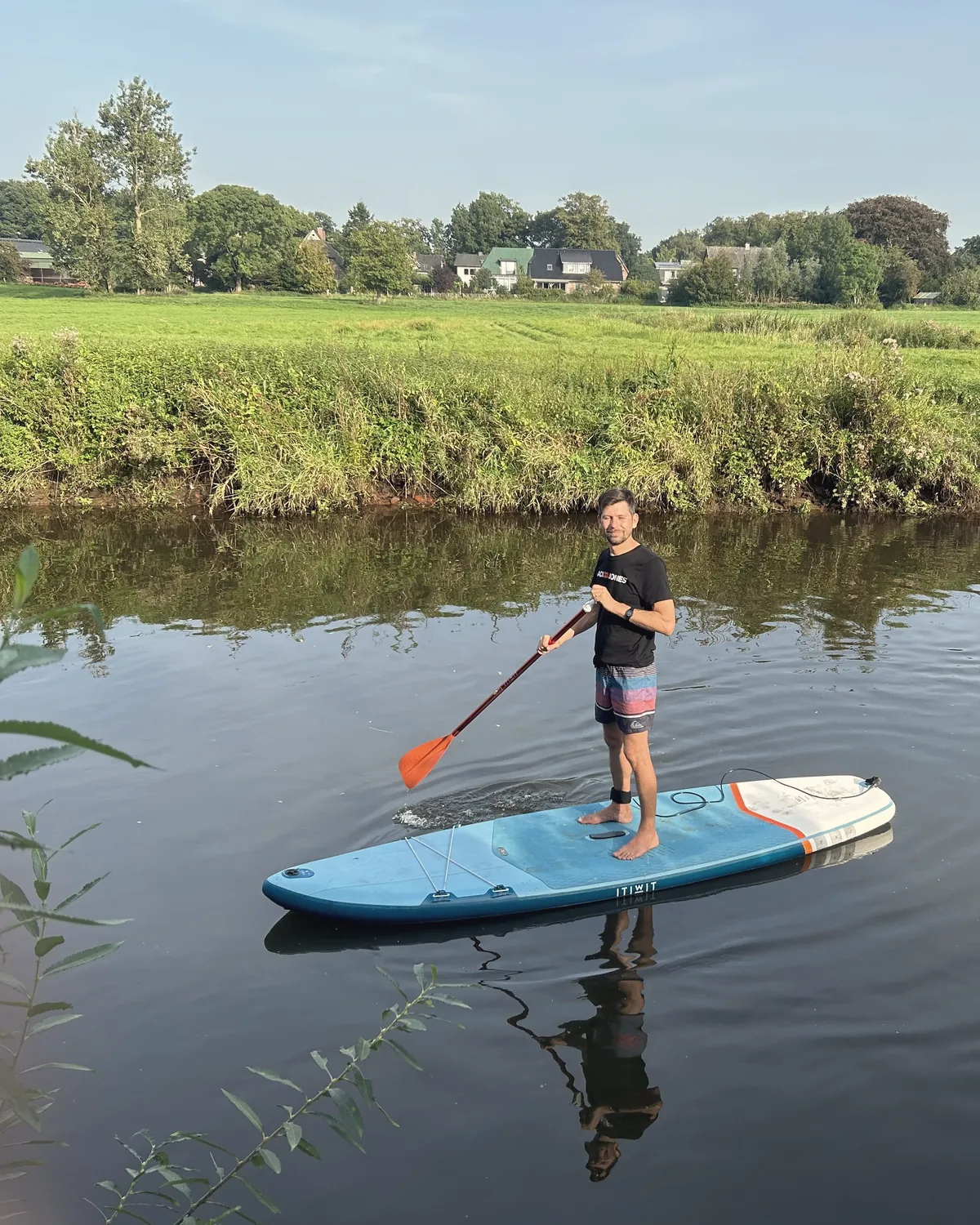 Till auf dem Stand-up-Paddle-Board auf einem ruhigen Fluss